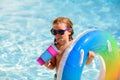 Happy kid playing with colorful swim ring in swimming pool on summer day. Child water toys. Children play in tropical Royalty Free Stock Photo