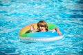 Happy kid playing with colorful swim ring in swimming pool on summer day. Child water toys. Children play in tropical Royalty Free Stock Photo