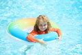 Happy kid playing with colorful swim ring in swimming pool on summer day. Child water toys. Children play in tropical Royalty Free Stock Photo