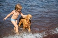 Happy kid playing with dog on beach. Little boy playing with dog in water. Royalty Free Stock Photo