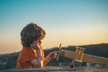 Happy kid playing with toy airplane against blue sky background. Cute child walking on a sunny summer day. Kids dreams Royalty Free Stock Photo