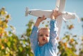 Happy kid playing with toy airplane against blue sky background. Cute child walking on a sunny summer day. Kids dreams Royalty Free Stock Photo