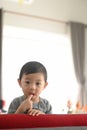 Happy kid putting fingers in his mouth with curious while sitting on sofa. Royalty Free Stock Photo