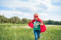happy kid in red superhero cape and mask running in meadow