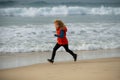 Happy kid running on sea beach. Funny boy run along surf edge. Child runner jogger running in the nature. Active healthy Royalty Free Stock Photo