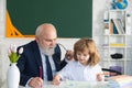 Happy kid in school. Old senior teacher help to writing. Education, teachering, elementary school. Royalty Free Stock Photo