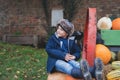 Happy kid sitting on big pumpkin patch,Cute boy having fun playing outdoor in Autumn park. Child playing outside for trick or teat Royalty Free Stock Photo