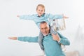 happy kid sitting on grandfather shoulders and imitating plane