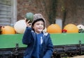 Happy kid sitting on hay patch holding pumpkin, boy having fun playing outdoor in Autumn park. Child playing outside for trick or Royalty Free Stock Photo