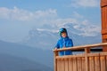 Happy skier teen on chalet balcony over stunning mountains
