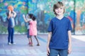 Happy kid smiling in schoolyard with other chilldren playing on