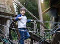 Happy kid standing on robe on tree house in playground Active child wearing jumper playing outdoor in forest park, Portrait little Royalty Free Stock Photo