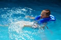 Happy kid in vest at swimming pool . Chilhood, leisure, swimming theme. Boy In Life Jacket