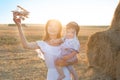 Happy kid and woman playing with toy airplane against field. Royalty Free Stock Photo