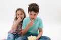 Happy kids, boy and girl eating popcorn, watching movie, smiling looking at camera, isolated on white studio background Royalty Free Stock Photo