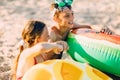 Happy kids boy and girl with an inflatable swimming circle, play and have fun sitting on the sand on the beach Royalty Free Stock Photo