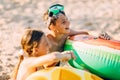 Happy kids boy and girl with an inflatable swimming circle, play and have fun sitting on the sand on the beach Royalty Free Stock Photo