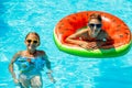 Happy kids, boy and girl in sunglasses, swim and play with inflatable rings in the pool, have fun during family summer vacation Royalty Free Stock Photo