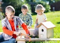 Happy kids brothers making wooden birdhouse by hands