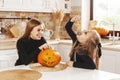 Happy kids celebrate Halloween in the kitchen at home in costumes and make-up with pumpkin lantern, have fun and laugh
