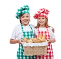 Happy kids with chef hats holding basket with bakery products