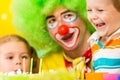 Happy kids and clown blowing candles on cake