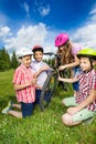 Happy kids in colorful helmets repair bike Royalty Free Stock Photo