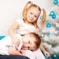 Happy kids cuddling near Christmas tree.