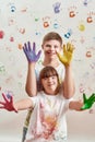 Happy kids, disabled boy and girl with Down syndrome smiling at camera, showing their hands painted in colorful paints Royalty Free Stock Photo