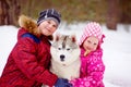 Happy kids embracing hasky dog in winter park