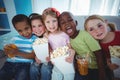 Happy kids enjoying popcorn and drinks while sitting Royalty Free Stock Photo