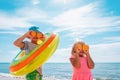 happy kids with fresh oranges and floatie on beach , concept of a healthy diet, vitamins, lifestyle Royalty Free Stock Photo