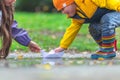 Happy kids girl and boy and colorful rubber boots playing with paper boat in puddle in autumn on nature Royalty Free Stock Photo