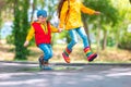 Happy kids girl and boy with umbrella and colorful rubber rain boots playing outdoor and jumping in rainy puddle Royalty Free Stock Photo