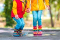 Happy kids girl and boy with umbrella and colorful rubber rain boots playing outdoor and jumping in rainy puddle Royalty Free Stock Photo