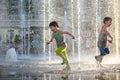 Happy kids have fun playing in city water fountain on hot summer