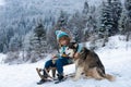 Happy kids having fun and riding the sledge in the winter snowy forest, enjoy winter season. Kids hug embrace dog husky. Royalty Free Stock Photo