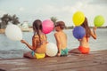 Happy kids holding color balloons while sitting on the beach Royalty Free Stock Photo