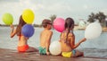 Happy kids holding color balloons while sitting on the beach Royalty Free Stock Photo