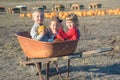 Happy kids sitting inside wheelbarrow at field pumpkin patch Royalty Free Stock Photo