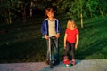 Happy kids-little boy with scooter and girl on skateboard ride outside Royalty Free Stock Photo