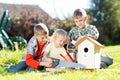 Happy kids making wooden birdhouse by hands. Older child teaches his younger brother.