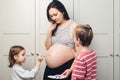 Happy kids painting pregnant belly their mother. Baby birth expecting time and belly painting