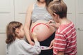 Happy kids painting pregnant belly their mother. Baby birth expecting time and belly painting Royalty Free Stock Photo