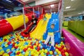 Happy kids playing at indoor play center playground. Children slides in colored slide into balls in ball pool Royalty Free Stock Photo