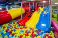 Happy kids playing at indoor play center playground. Children slides in colored slide into balls in ball pool Royalty Free Stock Photo