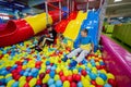 Happy kids playing at indoor play center playground. Children slides in colored slide into balls in ball pool Royalty Free Stock Photo