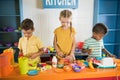 Happy kids playing with a toy kitchen in children room. Royalty Free Stock Photo