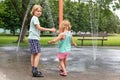 Happy kids playing at water splash pad fountain in park playground on hot summer day Royalty Free Stock Photo