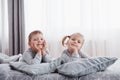 Happy kids playing in white bedroom. Little boy and girl, brother and sister play on the bed wearing pajamas. Nightwear Royalty Free Stock Photo